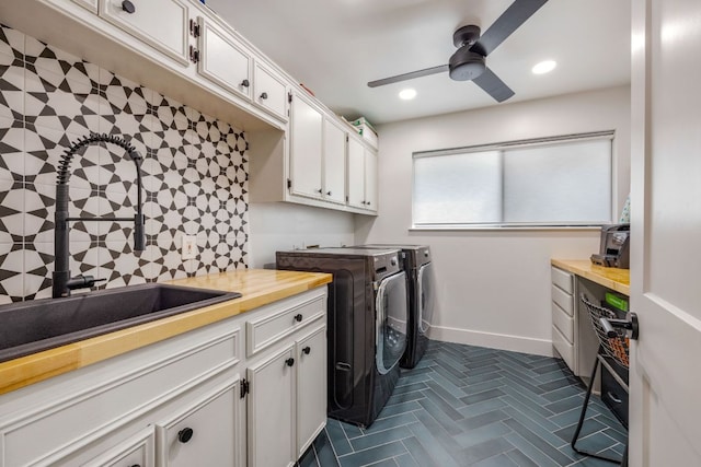laundry area with cabinet space, ceiling fan, a sink, separate washer and dryer, and baseboards
