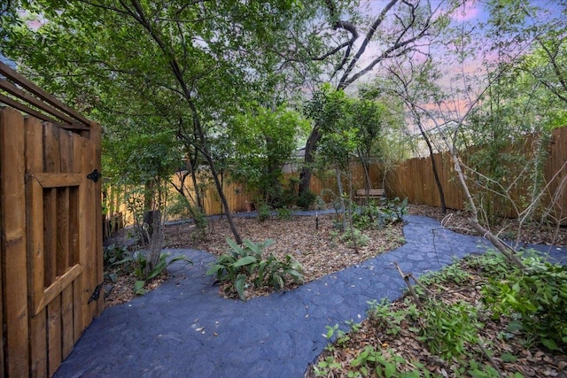 yard at dusk with a fenced backyard and a patio area