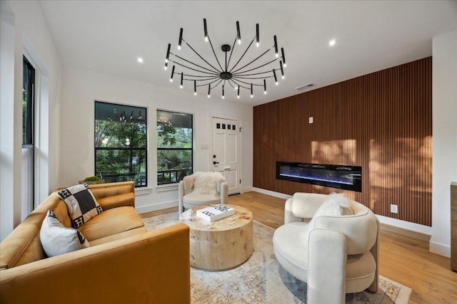 living room featuring visible vents, an accent wall, baseboards, wooden walls, and light wood finished floors