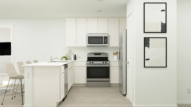 kitchen featuring appliances with stainless steel finishes, a sink, white cabinets, a peninsula, and light wood-style floors