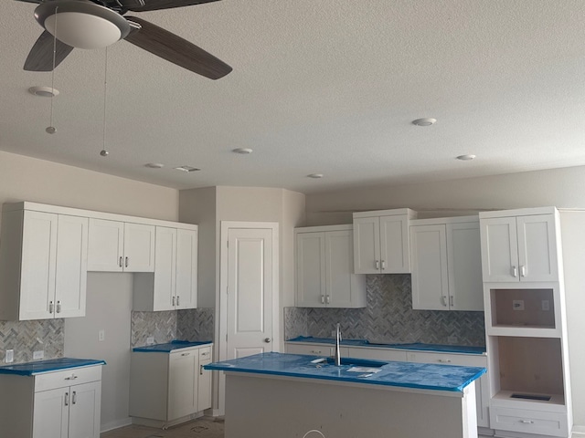 148 Golden Sage Ave, Georgetown, TX 78633 - kitchen featuring a kitchen island with sink, tasteful backsplash, ceiling fan, a textured ceiling, and white cabinets