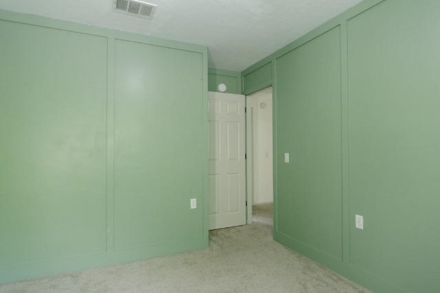 5711 Steven Creek Way, Austin, TX 78721 - unfurnished bedroom featuring light colored carpet, visible vents, and a decorative wall