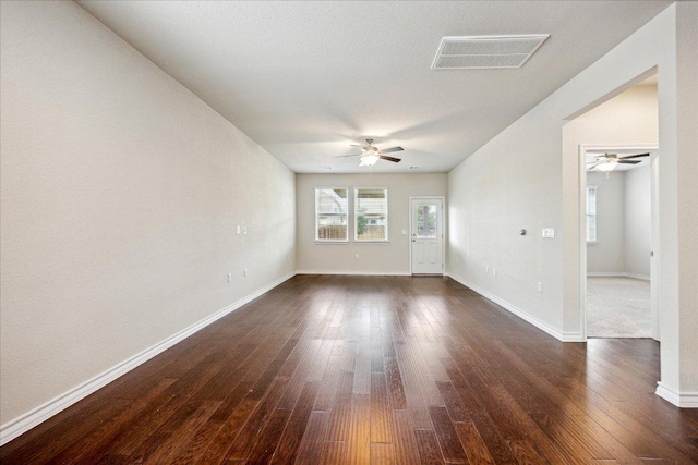 unfurnished room featuring visible vents, baseboards, ceiling fan, and dark wood-style floors