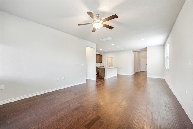 unfurnished living room featuring dark wood-style flooring, ceiling fan, a sink, recessed lighting, and baseboards