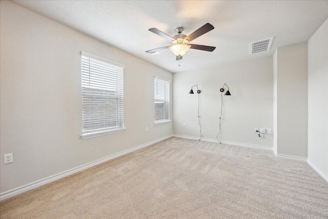 spare room featuring ceiling fan, visible vents, light carpet, and baseboards