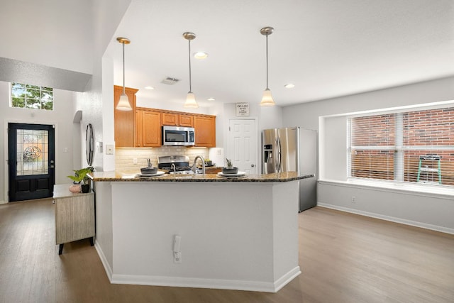 2104 Faldo Ln, Round Rock, TX 78664 - kitchen with stainless steel appliances, light wood finished floors, a peninsula, dark stone countertops, and recessed lighting