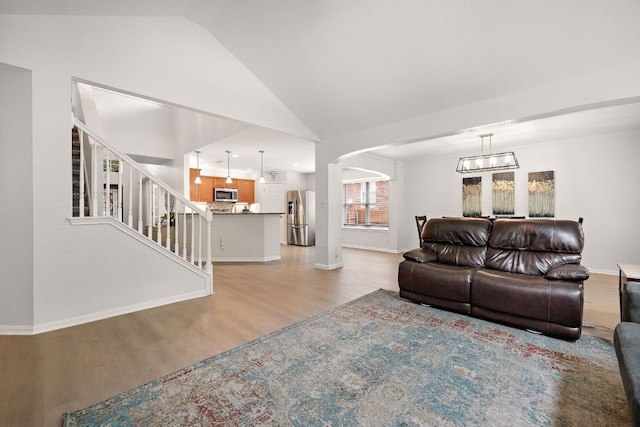 2104 Faldo Ln, Round Rock, TX 78664 - living area featuring light wood-style floors, lofted ceiling, baseboards, arched walkways, and stairs