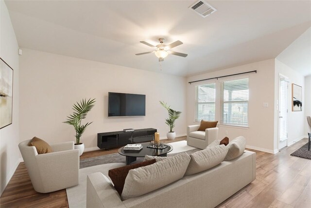 living room featuring visible vents, baseboards, ceiling fan, and wood finished floors