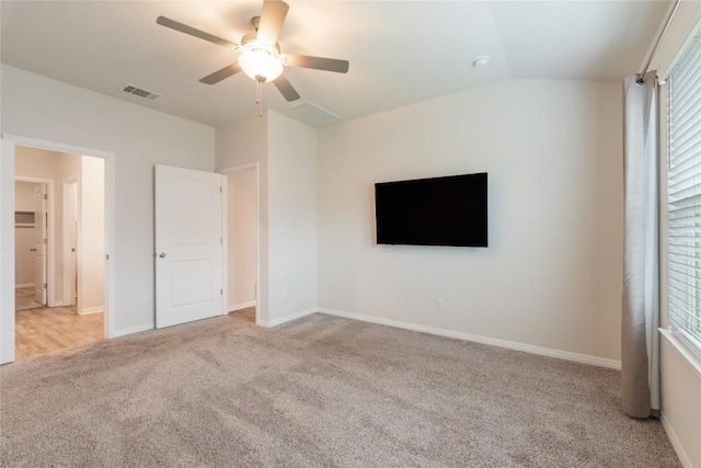 unfurnished bedroom featuring carpet flooring, a ceiling fan, baseboards, lofted ceiling, and visible vents