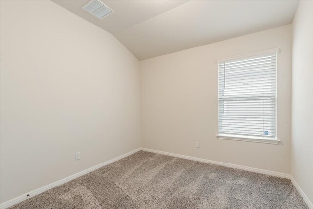 carpeted empty room featuring baseboards, visible vents, a healthy amount of sunlight, and vaulted ceiling