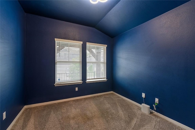 unfurnished room with carpet flooring, baseboards, and lofted ceiling