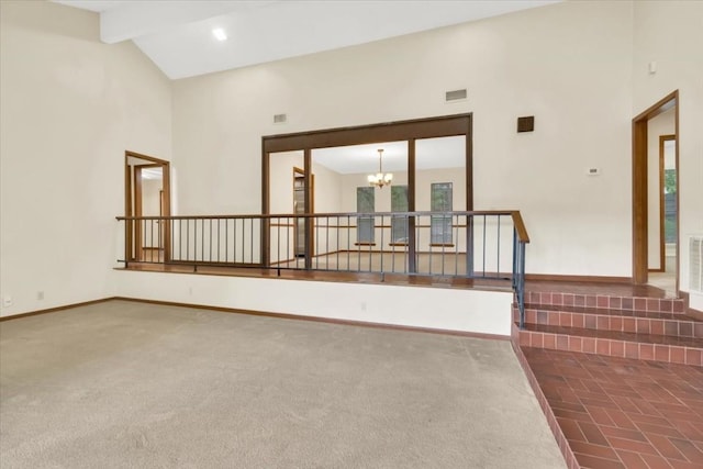 spare room with a notable chandelier, carpet floors, high vaulted ceiling, baseboards, and visible vents