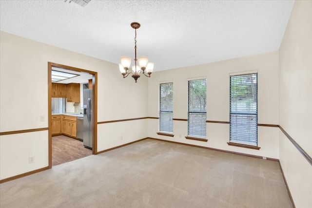 spare room with baseboards, a chandelier, light carpet, and visible vents
