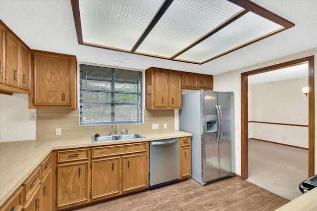 kitchen with a sink, light countertops, brown cabinetry, stainless steel appliances, and tasteful backsplash