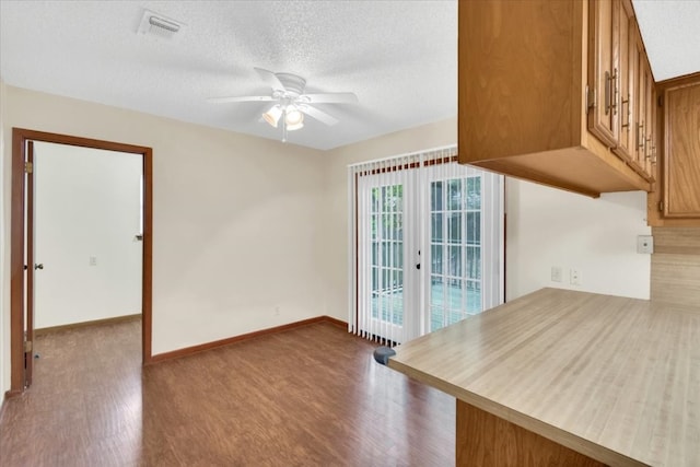 interior space featuring a textured ceiling, ceiling fan, visible vents, and wood finished floors