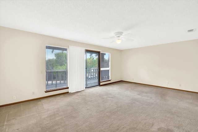 empty room with carpet floors, ceiling fan, visible vents, and baseboards