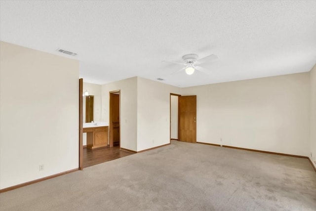 spare room with visible vents, carpet flooring, baseboards, and a ceiling fan