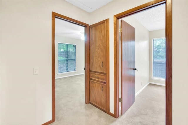 corridor featuring baseboards and light colored carpet