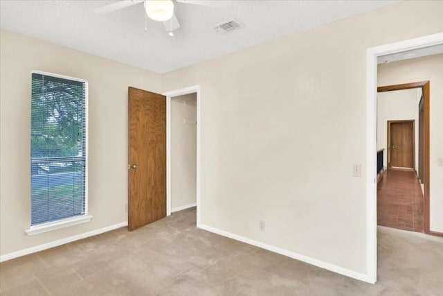 unfurnished room featuring visible vents, carpet flooring, baseboards, and a ceiling fan