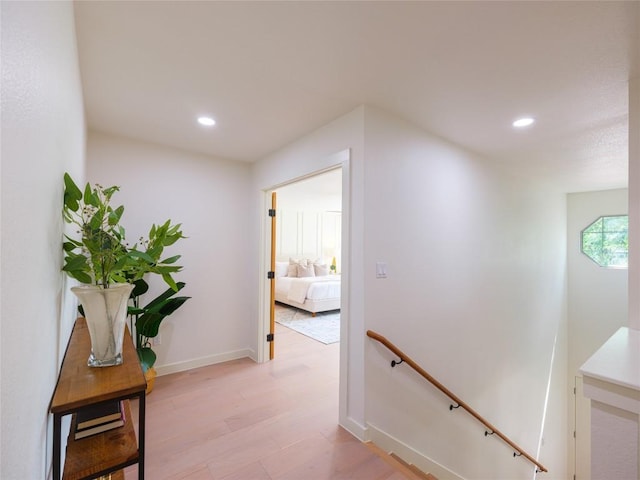 corridor featuring recessed lighting, baseboards, an upstairs landing, and light wood-style floors