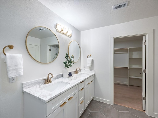 bathroom with double vanity, visible vents, a sink, and tile patterned flooring