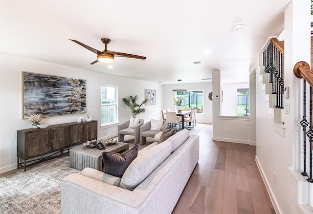 living room featuring baseboards, a ceiling fan, and wood finished floors
