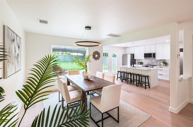dining space featuring visible vents, light wood-style floors, and baseboards