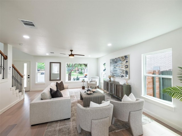 living room featuring stairs, recessed lighting, baseboards, wood finished floors, and visible vents