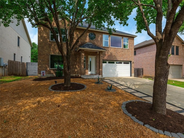 traditional-style house with a garage, fence, concrete driveway, and brick siding