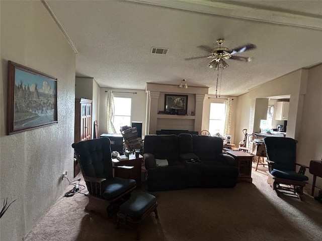 carpeted living area featuring a ceiling fan, visible vents, a wealth of natural light, and a fireplace