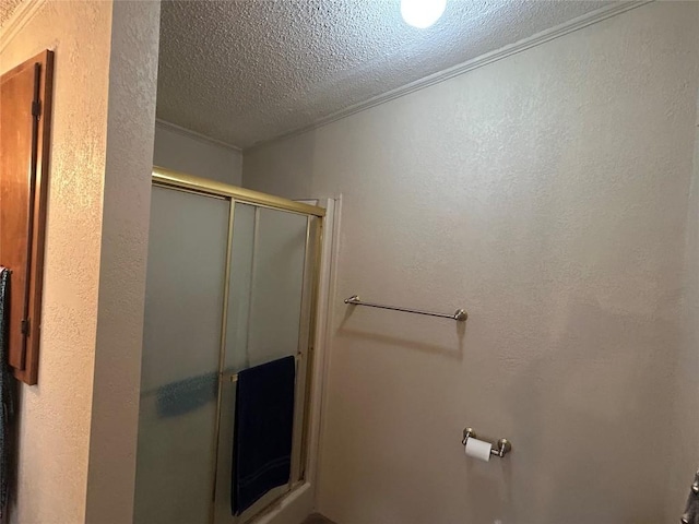 full bath featuring crown molding, a textured ceiling, a textured wall, and a stall shower