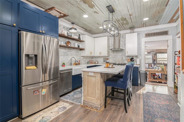 kitchen with wall chimney range hood, light countertops, stainless steel appliances, light wood-style flooring, and blue cabinetry