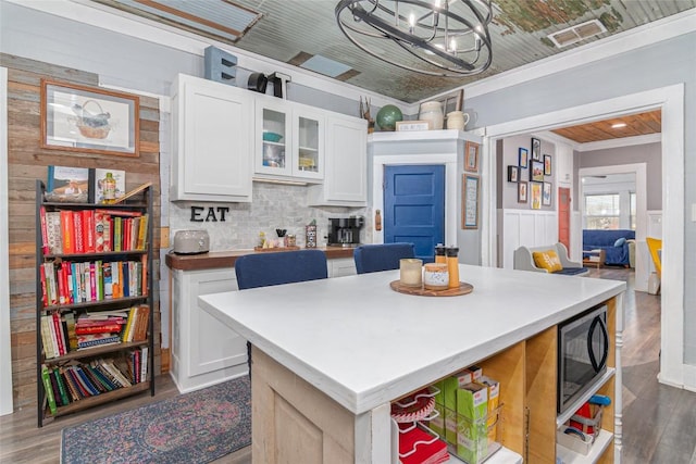kitchen with visible vents, black microwave, wood finished floors, white cabinets, and an inviting chandelier