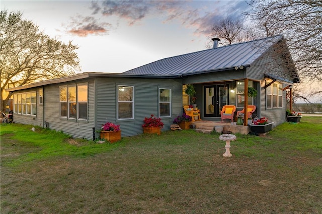 rear view of property featuring a yard, a standing seam roof, metal roof, and covered porch