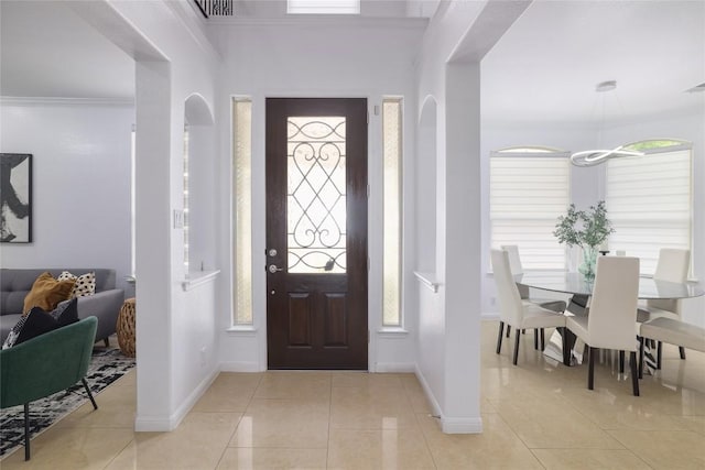 foyer entrance with crown molding, light tile patterned flooring, baseboards, and visible vents