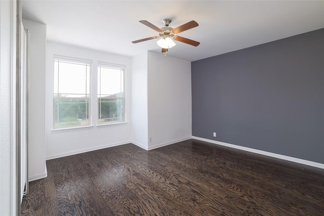 unfurnished room with baseboards, a ceiling fan, and dark wood finished floors