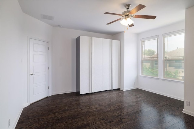 interior space with baseboards, dark wood finished floors, ceiling fan, and visible vents