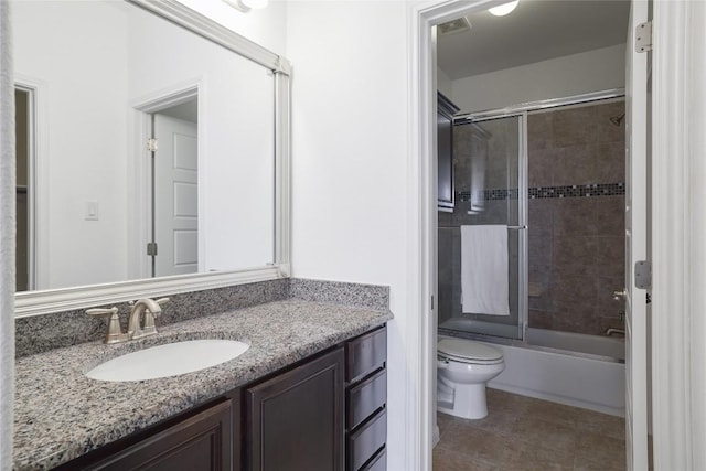 bathroom featuring vanity, toilet, tile patterned floors, visible vents, and bath / shower combo with glass door