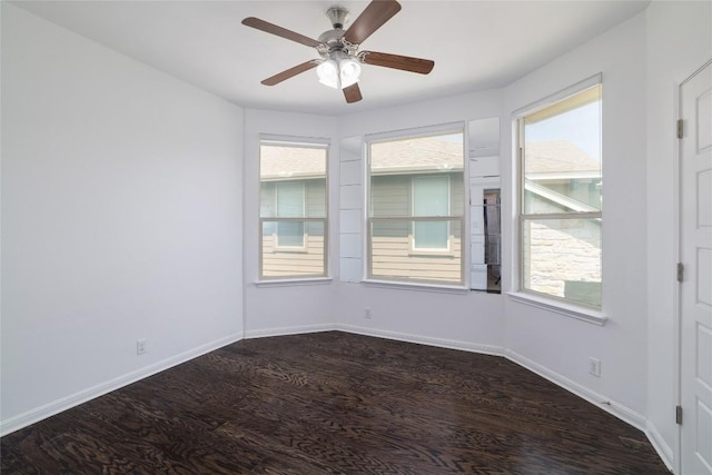 spare room with baseboards, plenty of natural light, a ceiling fan, and dark wood-type flooring