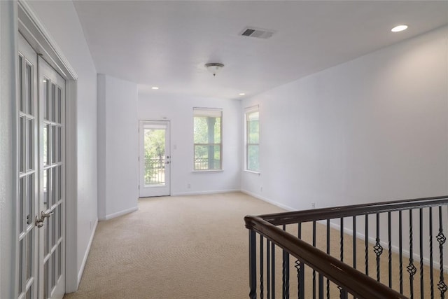 interior space with baseboards, light carpet, recessed lighting, and visible vents
