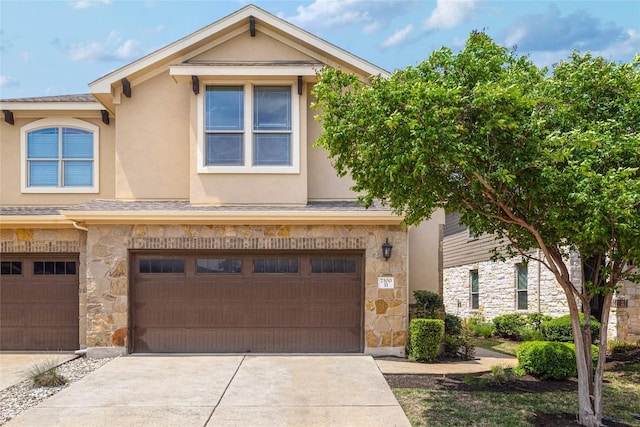 multi unit property with concrete driveway, an attached garage, stone siding, and stucco siding