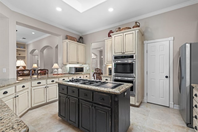 1901 Plantation Ct, Round Rock, TX 78681 - kitchen featuring stainless steel appliances, dark cabinetry, cream cabinets, a kitchen island, and crown molding