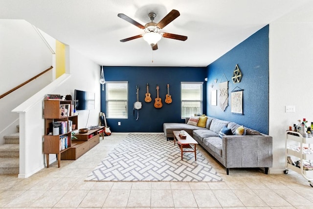tiled living room featuring stairway, plenty of natural light, ceiling fan, and an accent wall