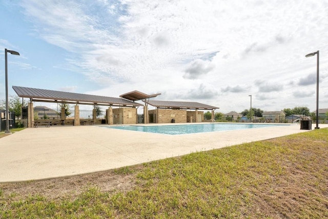 pool with a lawn, fence, and a patio area