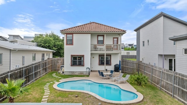 6006 Seville Dr, Austin, TX 78724 - rear view of house with a balcony, a fenced backyard, stucco siding, a patio area, and a tile roof
