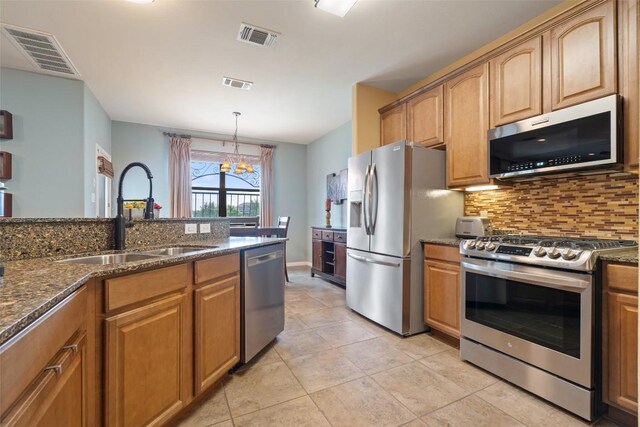 6006 Seville Dr, Austin, TX 78724 - kitchen featuring stainless steel appliances, decorative backsplash, a chandelier, dark stone countertops, and light tile patterned flooring