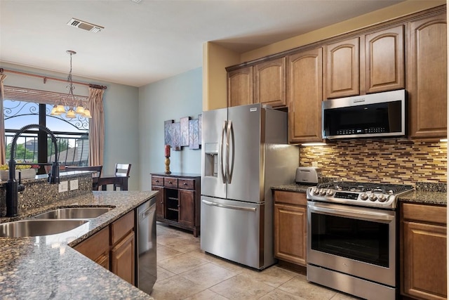 6006 Seville Dr, Austin, TX 78724 - kitchen with stainless steel appliances, a chandelier, dark stone countertops, and backsplash