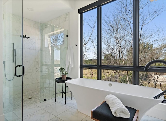 bathroom featuring a healthy amount of sunlight, a soaking tub, a shower stall, and marble finish floor