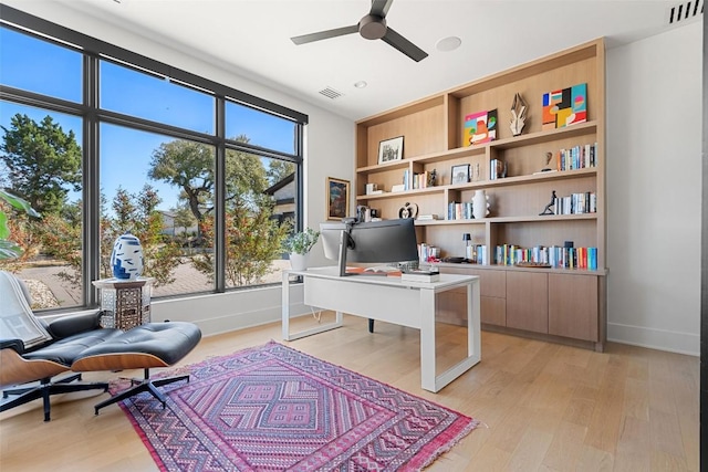 office area with visible vents, light wood-style floors, ceiling fan, and baseboards