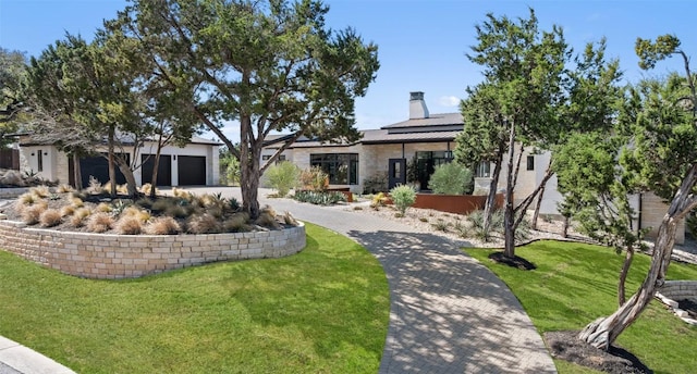view of front of home featuring a front yard, a chimney, a standing seam roof, driveway, and metal roof